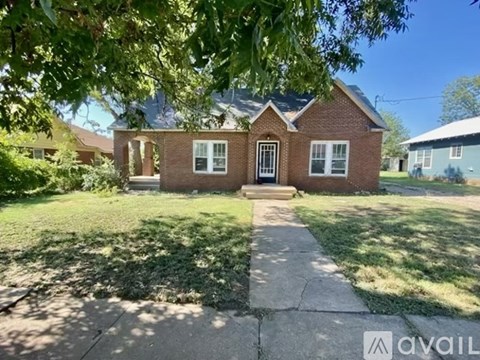 A brick house with a front yard and a walkway leading to the front door.