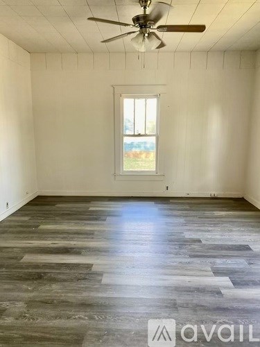 A room with wooden flooring and a ceiling fan.