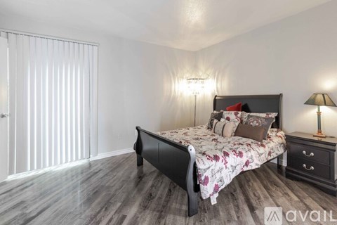 A bedroom with a large bed, a nightstand with a lamp, and a dresser with a drawer.