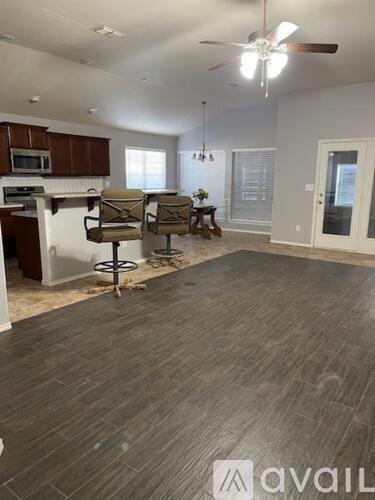 A living room with a grey floor and a ceiling fan.