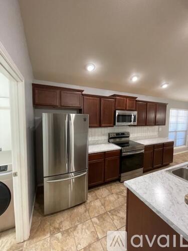 A kitchen with brown cabinets and a stainless steel refrigerator.