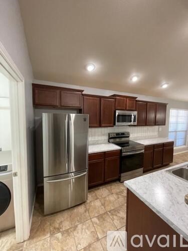 A kitchen with brown cabinets and a stainless steel refrigerator.