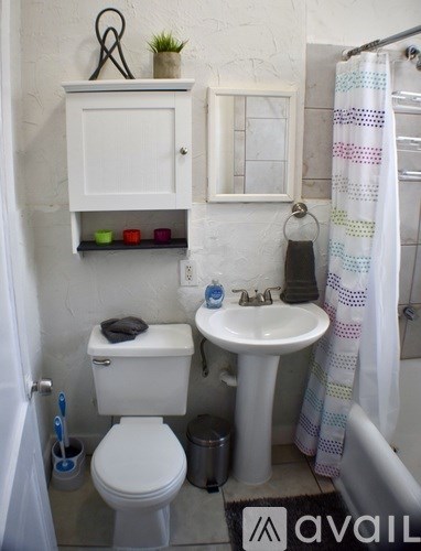 A small white bathroom with a toilet, sink, and a cabinet above it.
