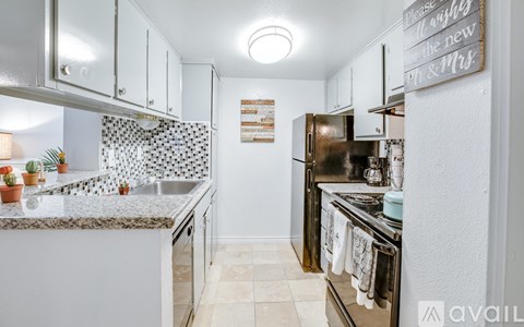 A kitchen with a white counter top and a refrigerator.