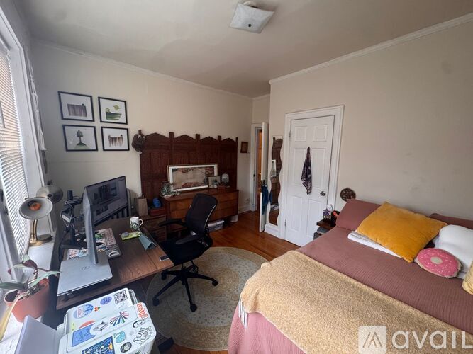 A room with wooden flooring and a window with a view of trees.