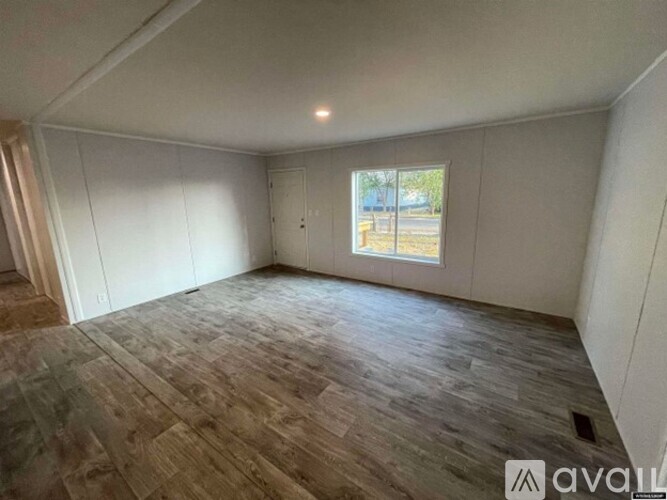 A room with wooden flooring and a window showing daylight outside.