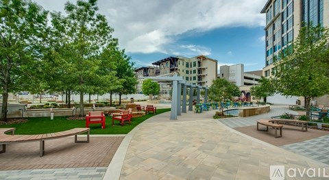 A park with benches and trees in the foreground and a building in the background.