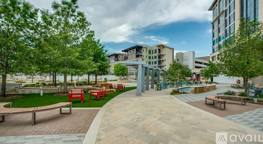 A park with benches and trees in the foreground and a building in the background.