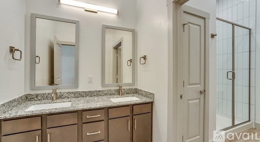 A bathroom with a granite countertop and a glass shower door.