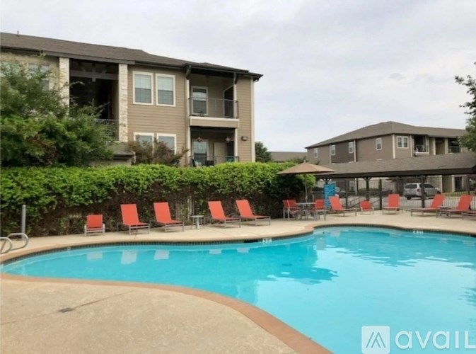 A swimming pool surrounded by red chairs and apartment buildings.