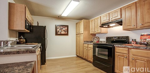 A kitchen with wooden cabinets and black appliances.