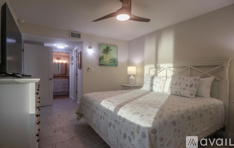 A bedroom with a bed, dresser, and ceiling fan.