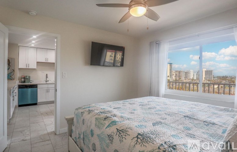 A bedroom with a bed, a ceiling fan, and a view of the city.