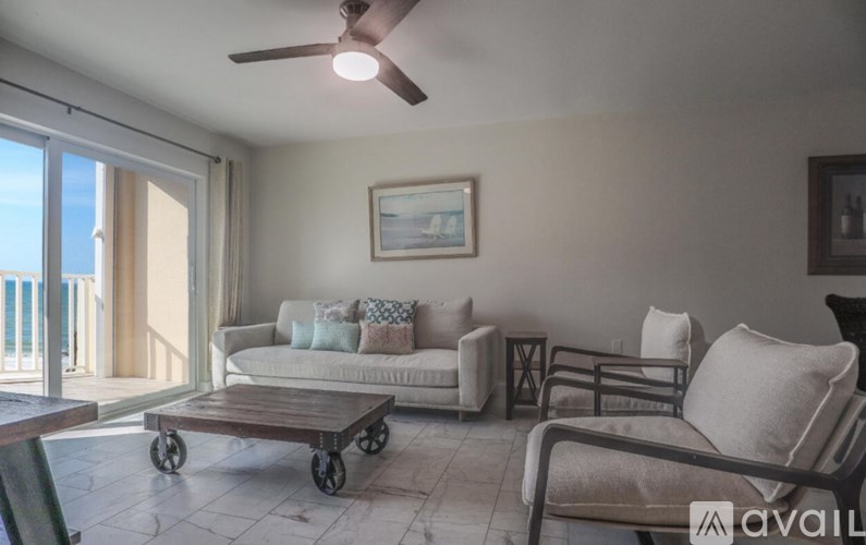 A living room with a couch, chairs, and a ceiling fan.