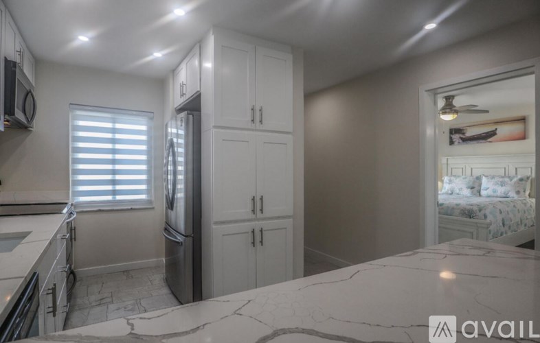 A kitchen with white cabinets and a marble countertop.