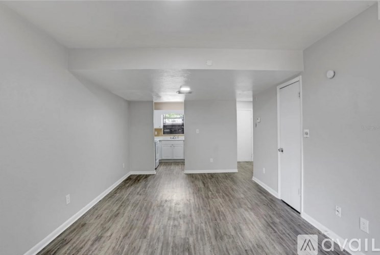 A spacious room with wood flooring and white walls.