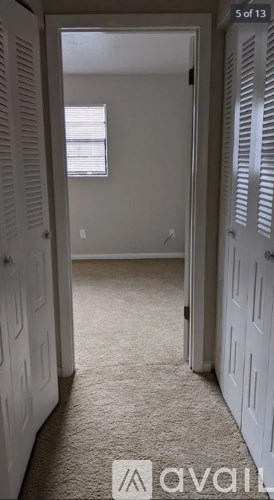 A hallway with white doors and carpeted floor.