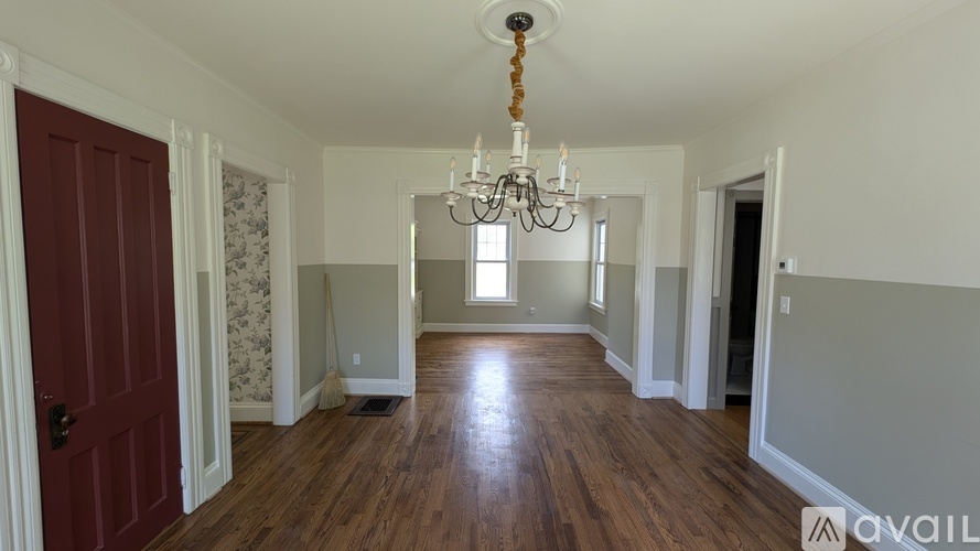 A room with a wooden floor and a chandelier hanging from the ceiling.
