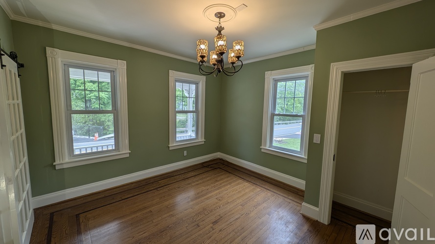 A room with green walls and wooden floors, with a chandelier hanging from the ceiling.
