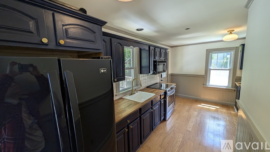 A kitchen with black cabinets and a black refrigerator.