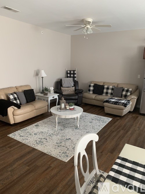 A living room with a beige couch, a white coffee table, and a white chair.