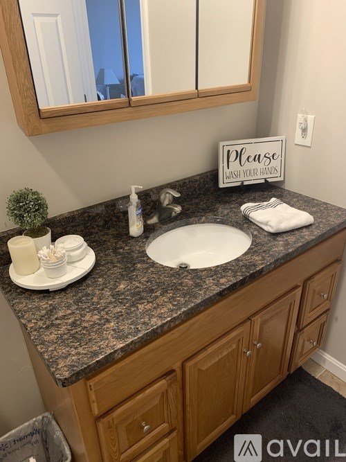 A bathroom sink with a sign that says "Please wash your hands.".