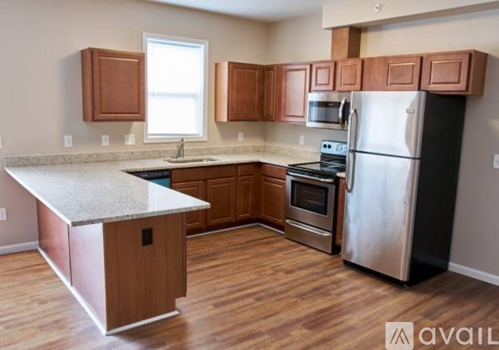 A kitchen with wooden cabinets and a stainless steel refrigerator.