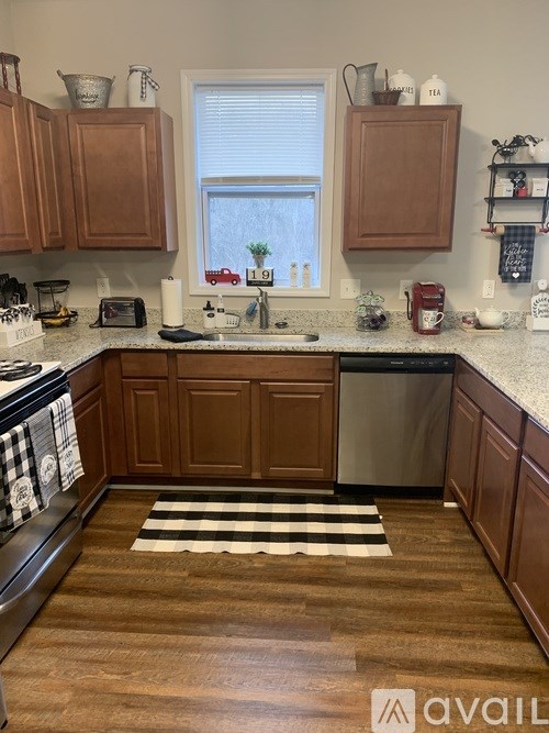 A kitchen with wooden cabinets and a black and white striped rug.