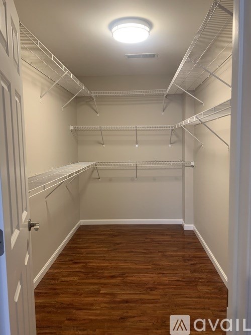A white closet with a light on the ceiling and wooden floors.