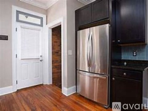 A kitchen with a stainless steel refrigerator and wooden floors.