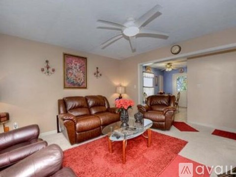 A living room with a red rug and brown leather furniture.