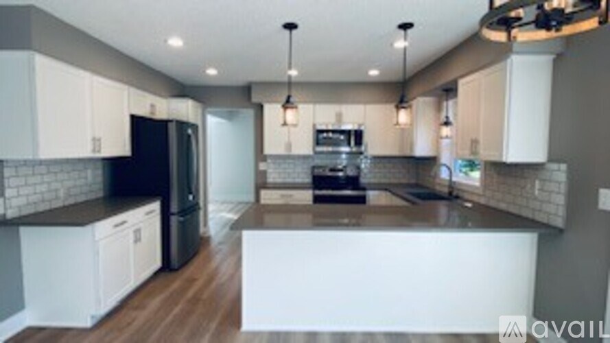 A modern kitchen with a black refrigerator and white cabinets.