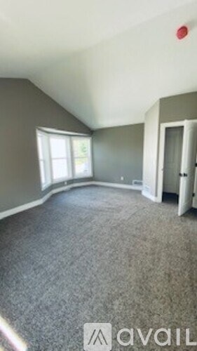 A room with grey carpet and a window.