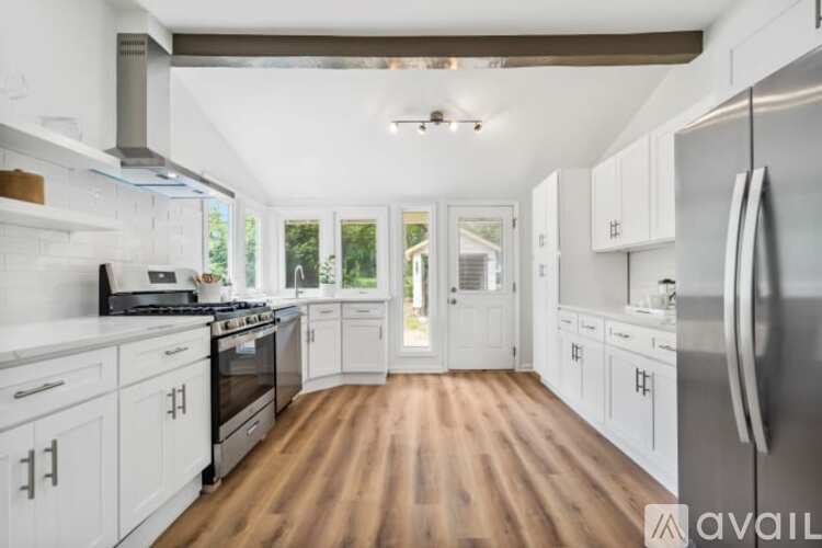 A modern kitchen with white cabinets and a wooden floor.