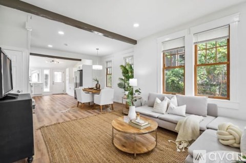 A living room with a white couch, a wooden coffee table, and a flat-screen TV.