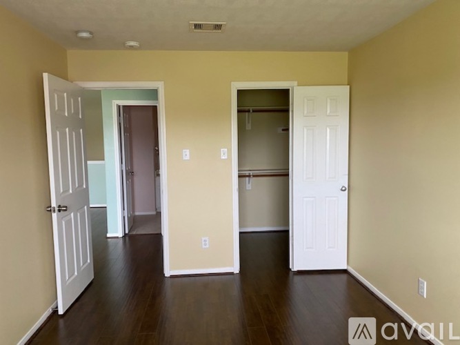 A room with white doors and brown floors.