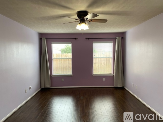 A room with a ceiling fan and two windows.