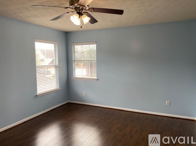 A room with a ceiling fan and two windows.