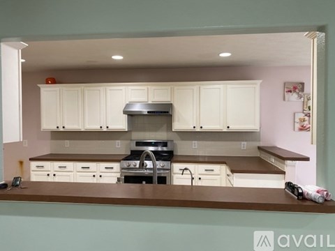 A kitchen with white cabinets and a brown countertop.