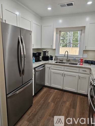 A kitchen with a stainless steel refrigerator and white cabinets.