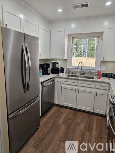 A kitchen with a stainless steel refrigerator and white cabinets.