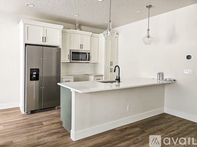 A kitchen with a refrigerator, microwave, and cabinets.