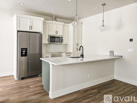A kitchen with a refrigerator, microwave, and cabinets.
