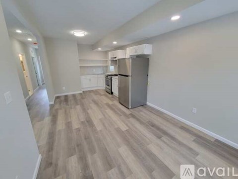A kitchen area with a refrigerator, cabinets, and a countertop.