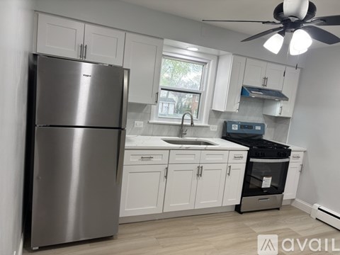 A modern kitchen with a stainless steel refrigerator and white cabinets.