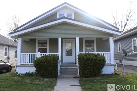 A house with a front porch and a car parked in front.