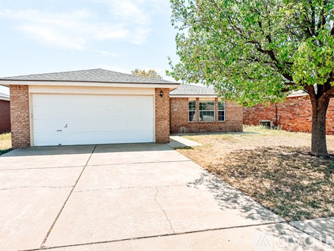 A house with a white garage door and a tree in front.