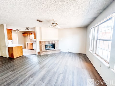 A spacious living room with wood flooring and a fireplace.