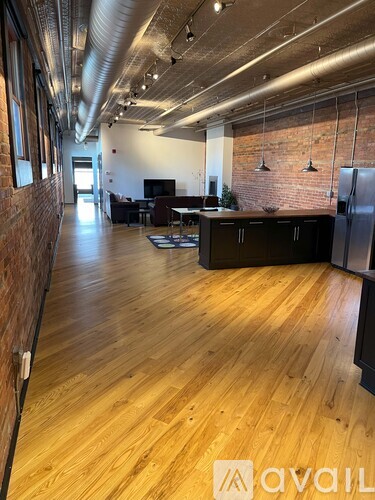 A large open space with wooden floors and exposed pipes on the ceiling.