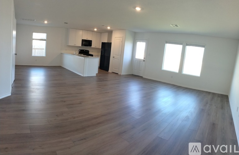 A spacious room with wooden flooring and white walls.